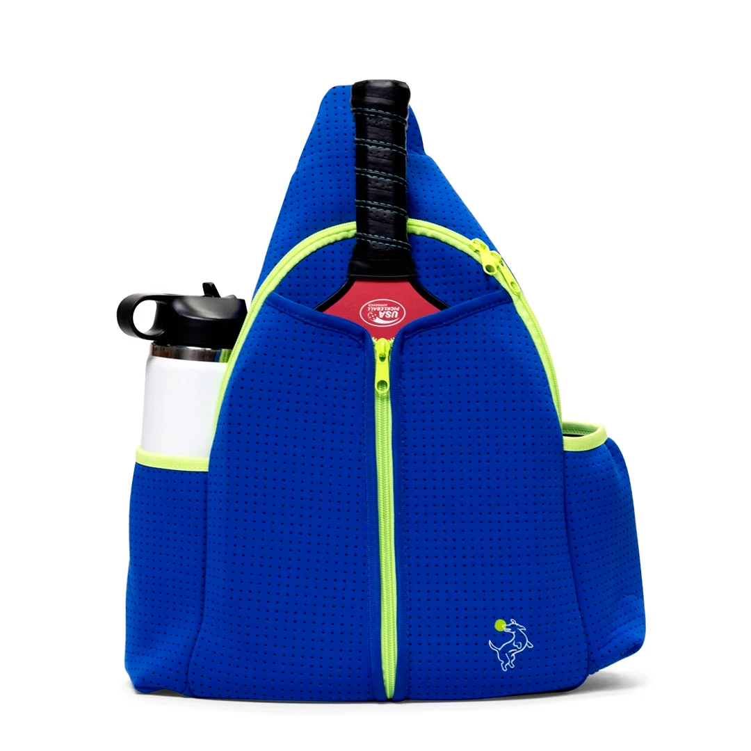 The Swinton Pickleball Paddle Sling Bag in royal blue features neon yellow zippers, a paddle handle peeking from the top compartment, a white water bottle in the left pocket, and a small white bull logo on the lower right.