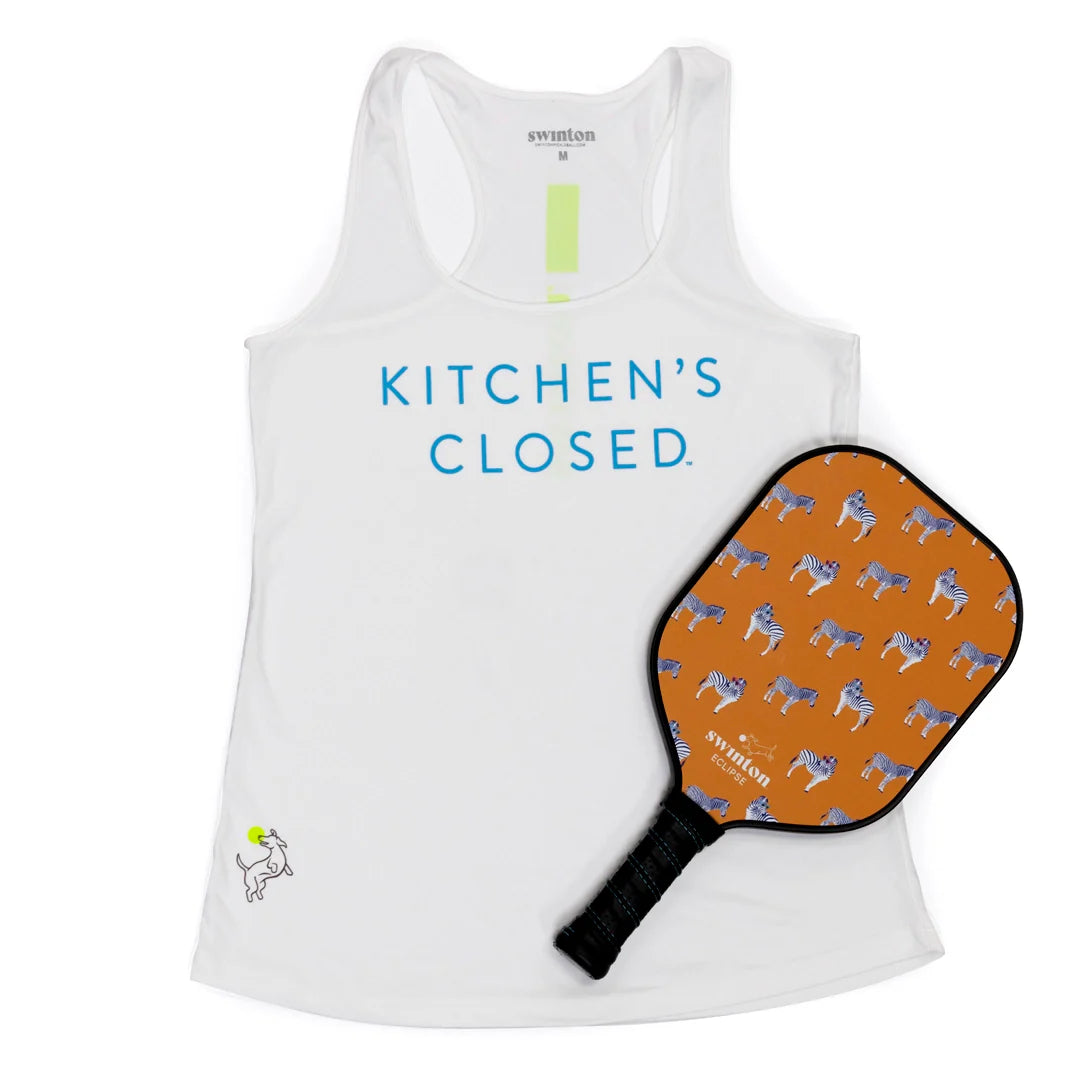 The Swinton Pickleball Performance Tank White features bold blue “KITCHEN’S CLOSED.” text and is paired with an orange zebra-patterned paddle—ideal for fans of fun and performance, both on and off the court.