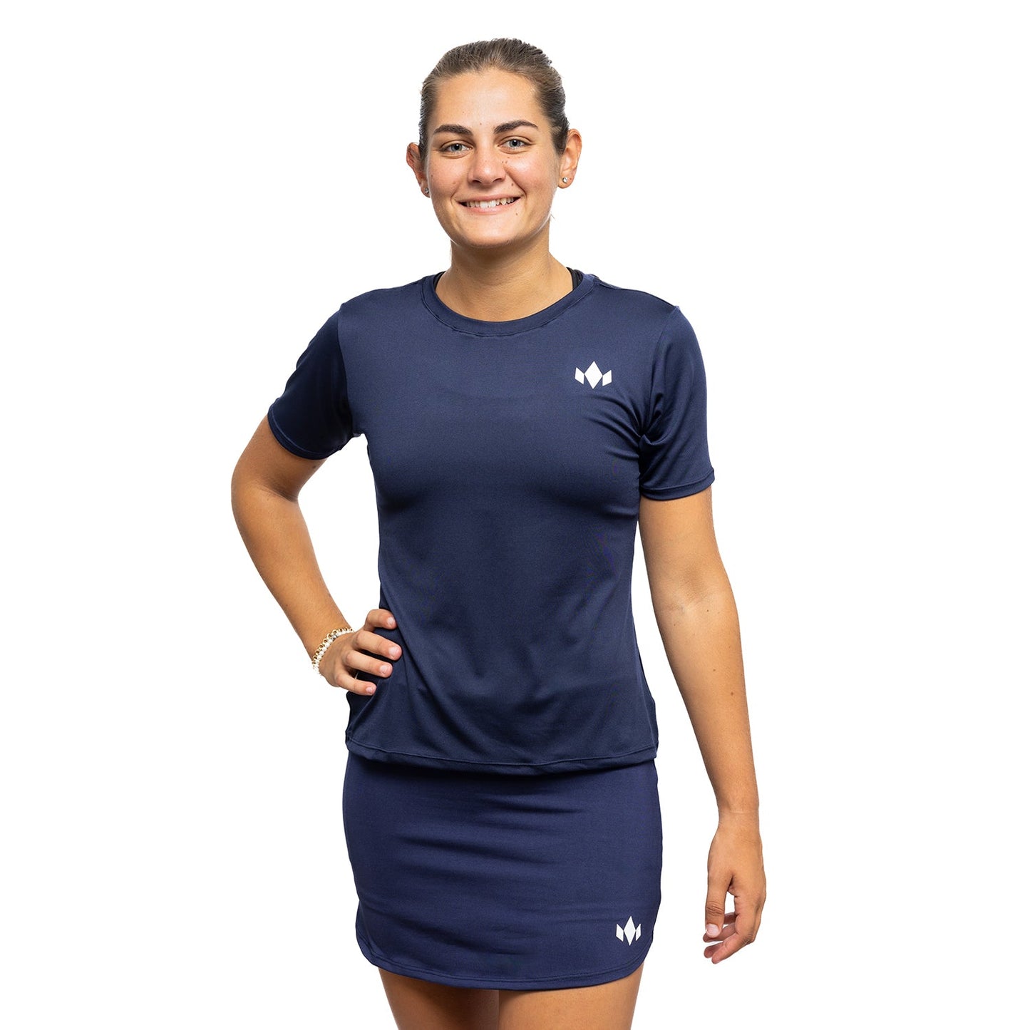 A woman stands against a white background, smiling with one hand on her hip. She wears the Diadem Sports Team Women's Essential Crewneck in navy blue, made from lightweight fabric and featuring a small white geometric logo on the left side.