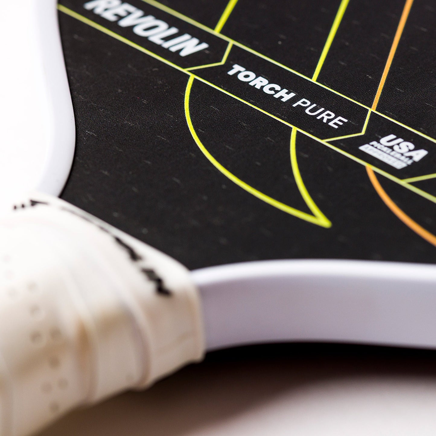 Close-up of the Torch Pure Pickleball Paddle by Revolin Sports, featuring neon yellow and orange lines, visible branding (REVOLIN, TORCH PURE, USA), and a partially visible white handle with a textured grip.