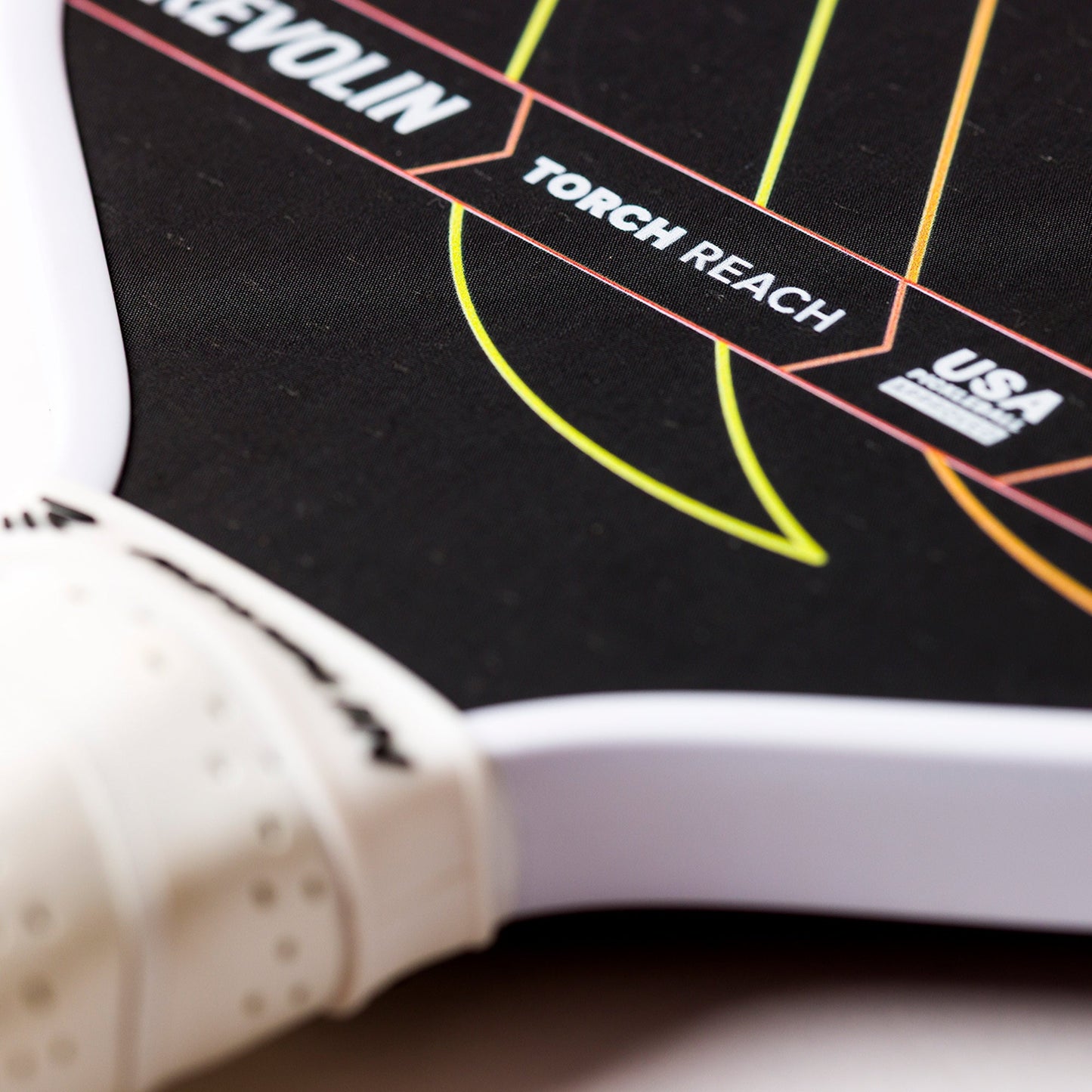 Close-up of the Revolin Sports Torch Reach Pickleball Paddle, a lightweight design featuring a white edge and handle, colorful curved lines, USA Pickleball Approved mark, polymer honeycomb core, and a dotted 3D-printed octagonal textured grip.