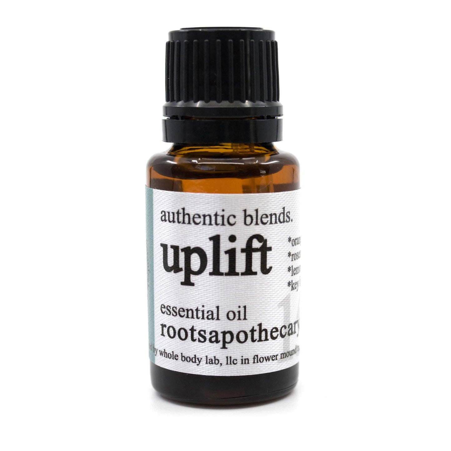 A brown glass bottle with a black screw cap labeled "Roots Apothecary Uplift Essential Oil Blend." Smaller text reads "Whole Body Lab, LLC, in Flower Mound, TX.