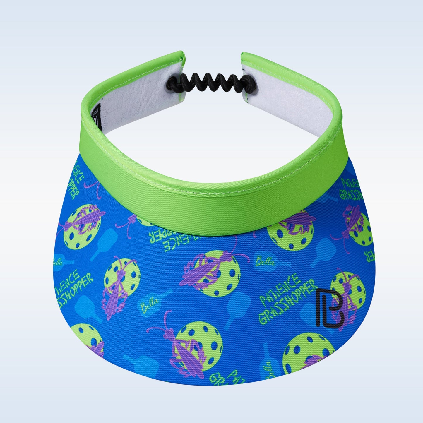 The PB Visor Patience Grasshopper by Pickleball Bella features a bright green band, blue brim, yellow and green pickleballs, purple paddles, "RELIEVE GRASSHOPPER" text, a black coiled strap, and a moisture-wicking headband.