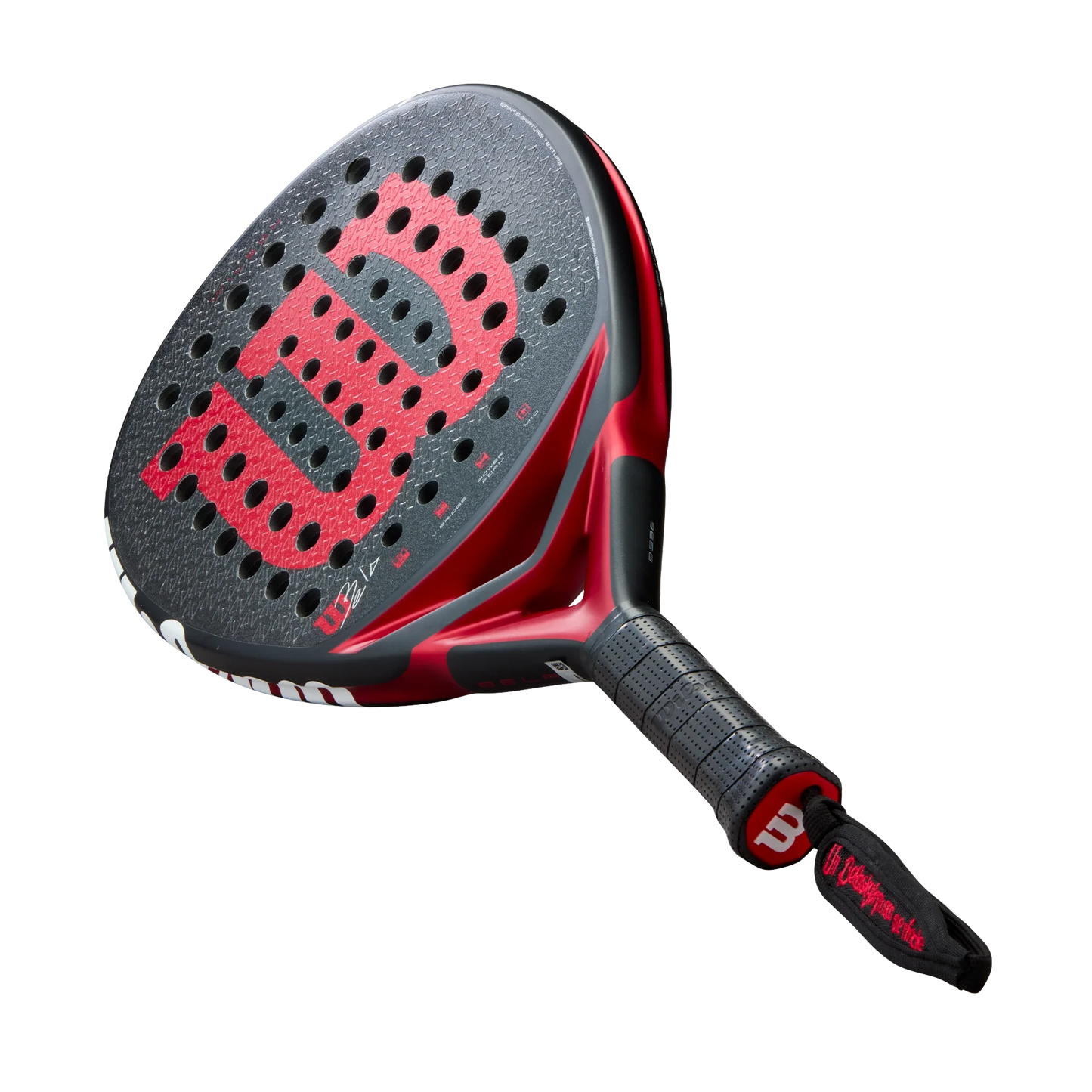 A close-up of the Wilson Bela V3 Padel Racket by Padel USA shows its textured 24K carbon black face with circular holes, bold red W logo, black grip with tape, and a black wrist strap with red text on a plain white background.
