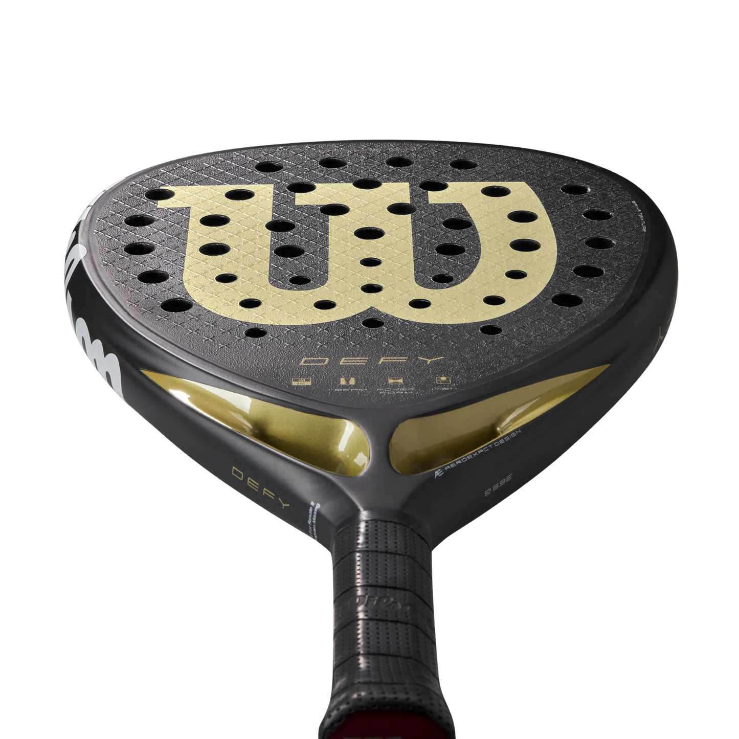 Close-up of the Wilson Defy V1 Padel Racket by Padel USA, featuring a black 3K Carbon Face with a large gold "W" logo, multiple circular holes, black grip handle with gold accents near the bridge, and "Defy" in gold below the logo.