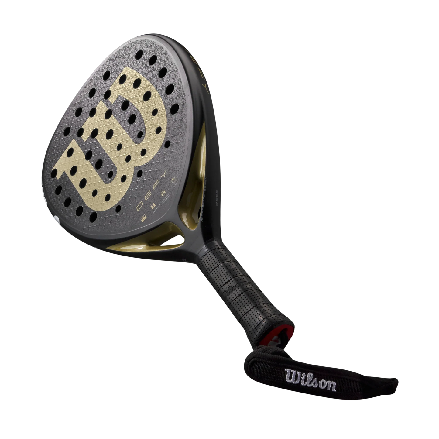 The Wilson Defy V1 Padel Racket by Padel USA features a black design with a gold "W" logo, 3K Carbon Face for power and spin, round perforations, textured grip, and a Wilson-branded wrist strap on a plain white background.