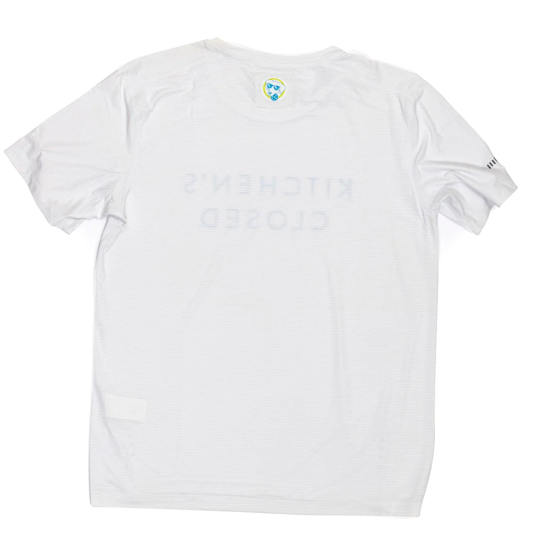 The Swinton Pickleball Women's Lux Performance White Kitchen's Closed Tee is a moisture-wicking shirt with blue text, designed for active comfort.